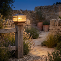 Rame copper pillar lantern on a timber fence post lighting a flagstone garden path at dusk