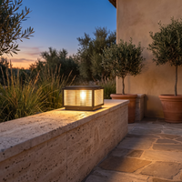 Rialto pillar light on a travertine courtyard wall beside a flagstone path at dusk