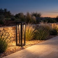Single Stelo bollard light at the edge of a gravel planting bed at dusk