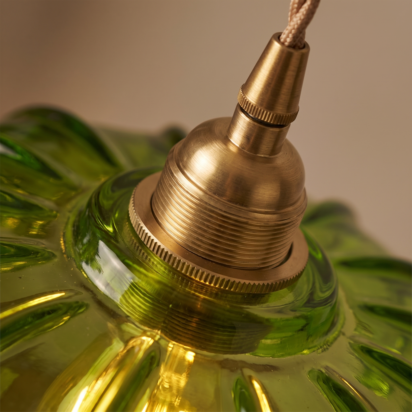 Macro detail of the brushed brass collar and cord fitting on the Fiora pendant light