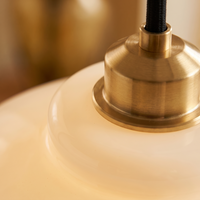 Macro detail of the polished brass collar where the fitting meets the Lattea glass shade