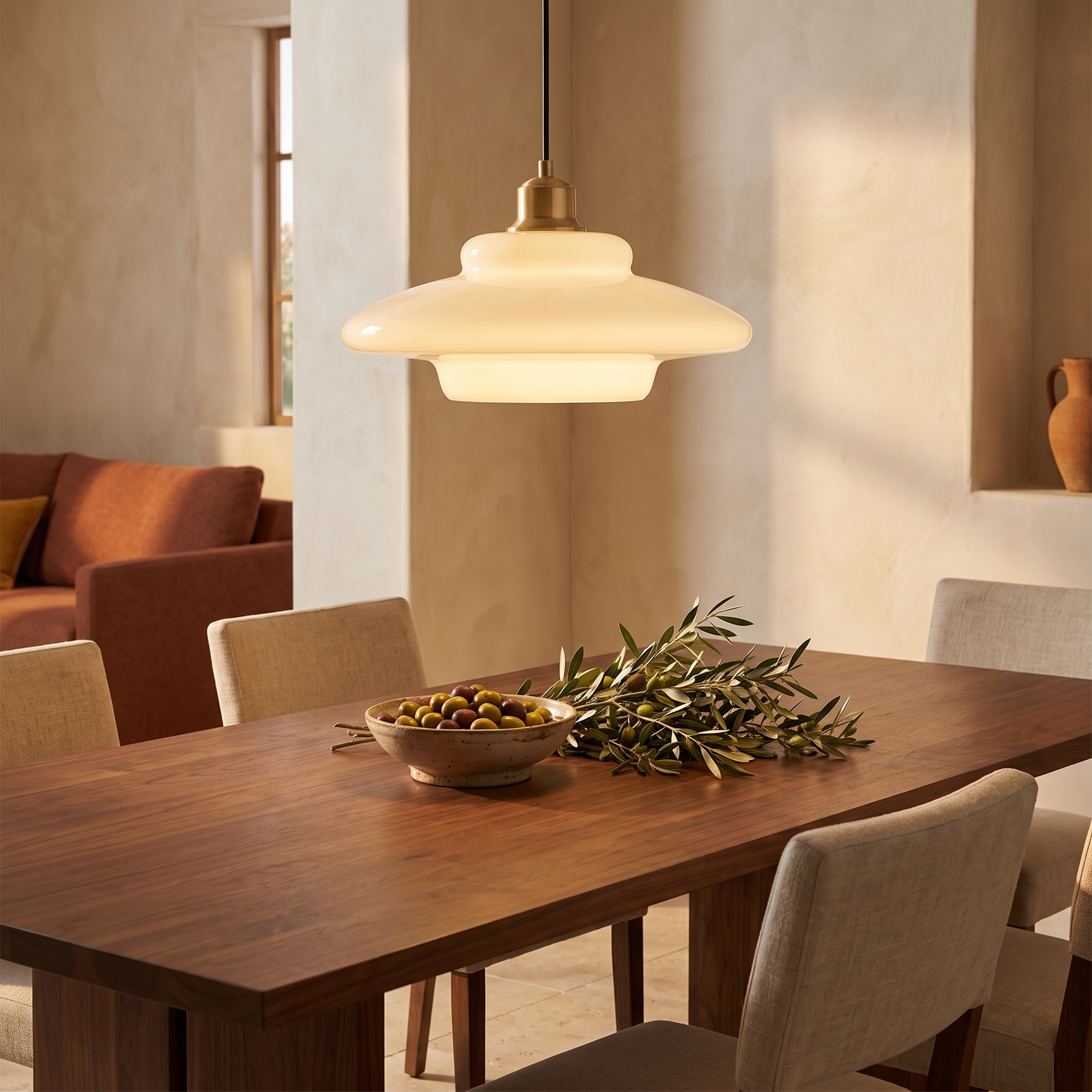 Lattea milk glass pendant hanging above a walnut dining table in warm evening light