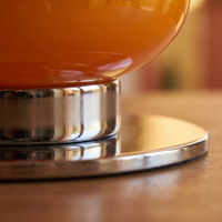 Macro detail of the polished chrome base and the seat where glass meets metal on the Bellona lamp