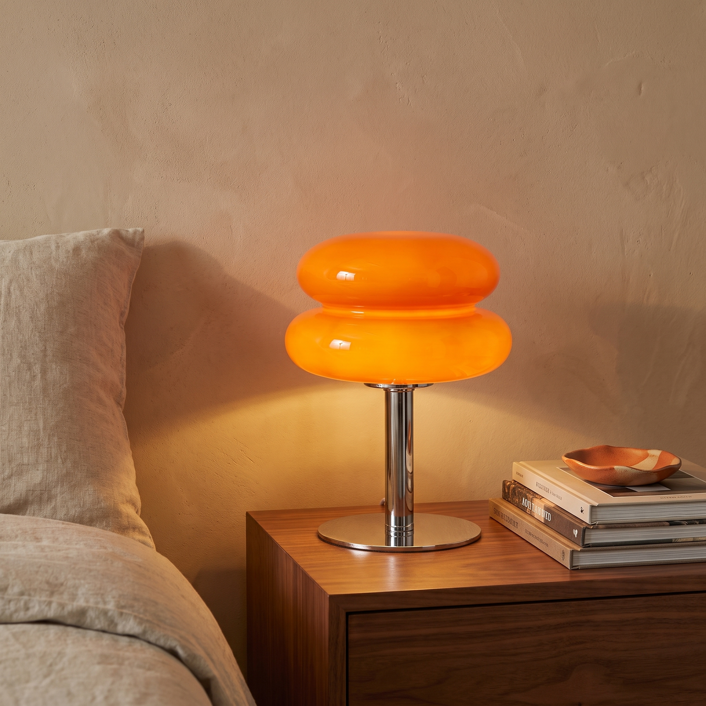 Bellona glass table lamp lit on a walnut bedside table against a limewashed plaster wall